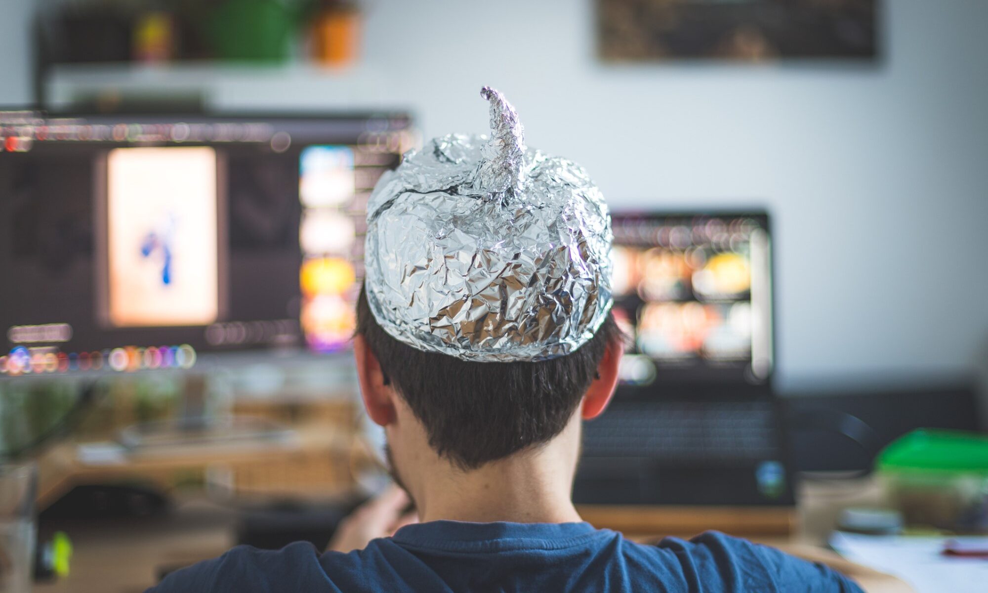 photograph of person in tin foil hat consuming media